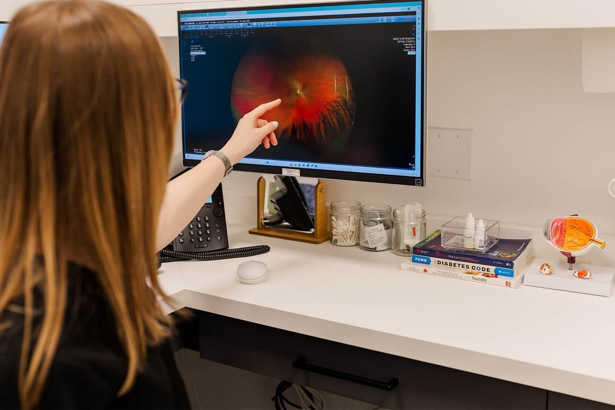 A West 5 Optometry team member reviewing a wide field retinal image on the exam room monitor